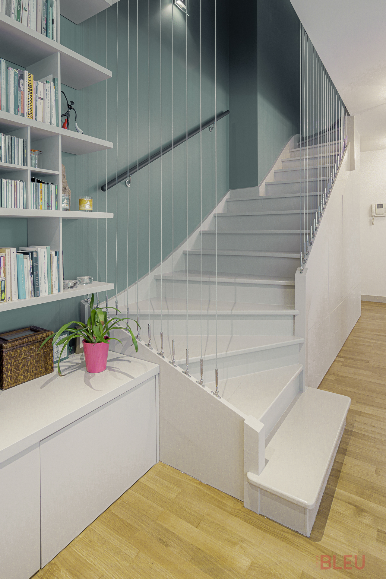 L'escalier d'origine est lourd et sombre, ne correspondant pas aux goûts des résidents. Les garde-corps sont supprimés, le bois est décapé et poncé pour effacer les marques du temps. Des filins et une main courante sont ajoutés pour améliorer l'accessibilité. Une peinture époxy noire unifie l'escalier avec le dressing de l'entrée. Le résultat est fonctionnel, léger et moderne malgré l'utilisation de l'ancien escalier.