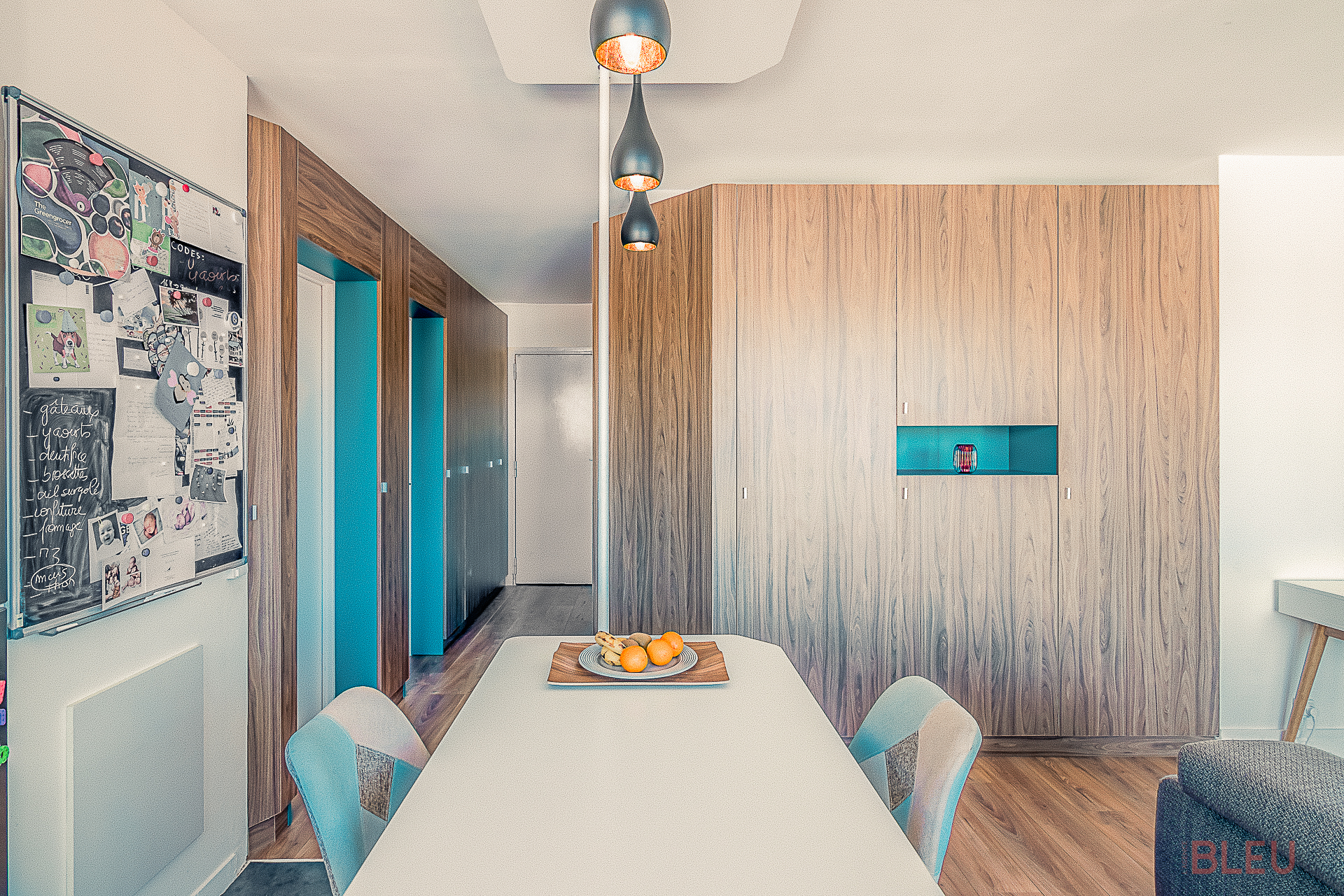Intérieur moderne et bien agencé d'un appartement parisien avec salle à manger ouverte, table blanche et luminaires coniques.