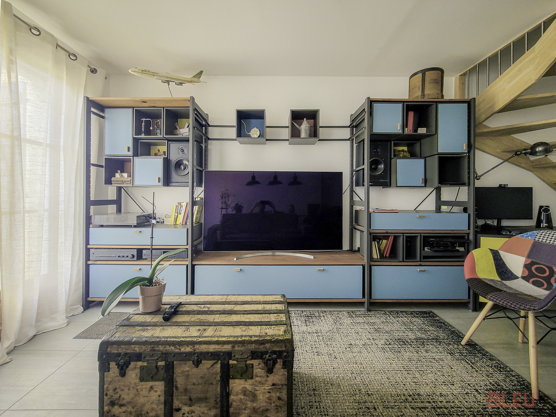 Espace de vie éclectique avec unité de rangement industrielle, malle vintage et chaise patchwork - Projet de rénovation appartement à Montrouge par notre agence d'architecture intérieur Paris
