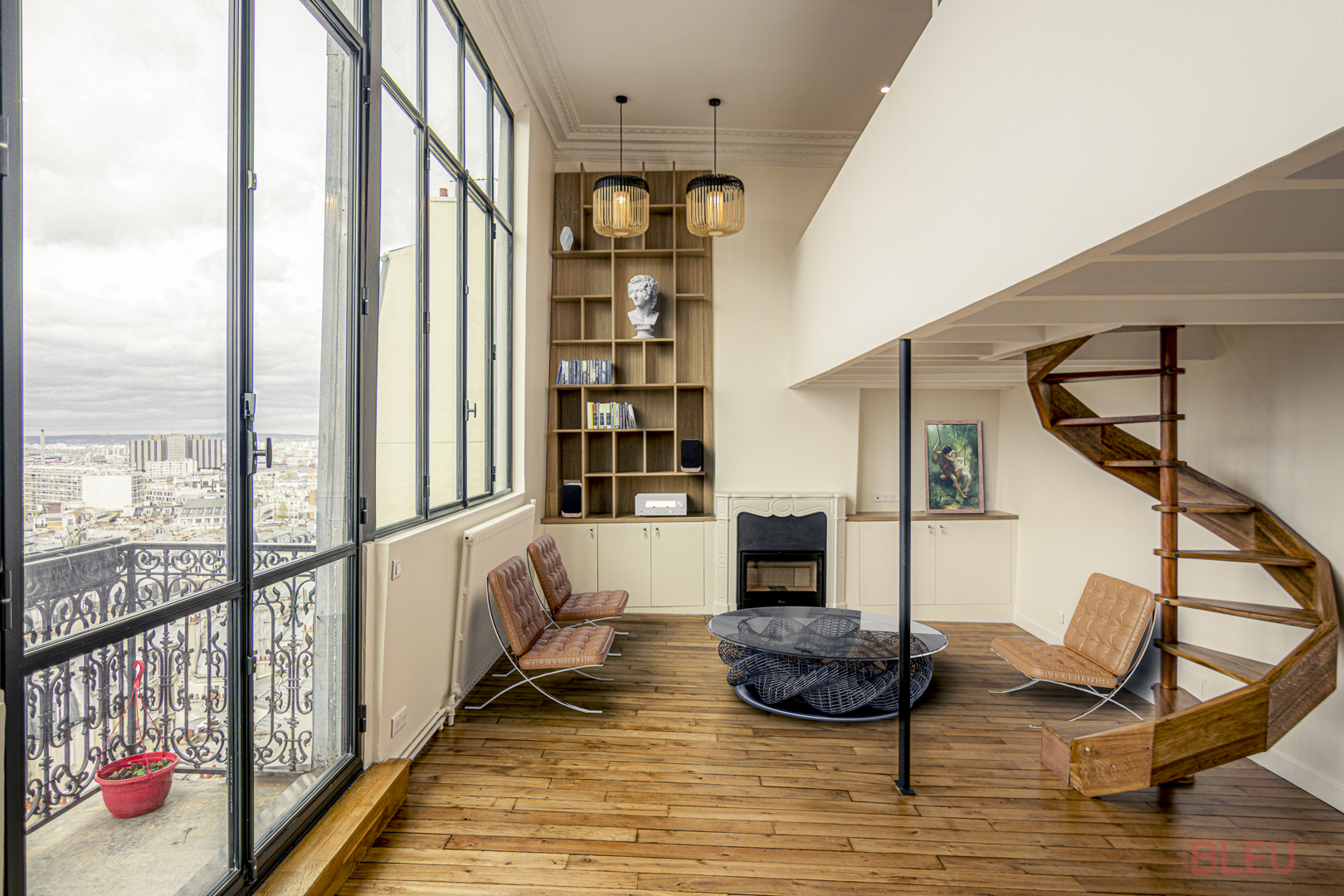 Espace de vie moderne avec grandes fenêtres et escalier en colimaçon en bois, conçu par un architecte intérieur Paris pour un projet de rénovation loft avec éléments haussmanniens et décoration élégante.